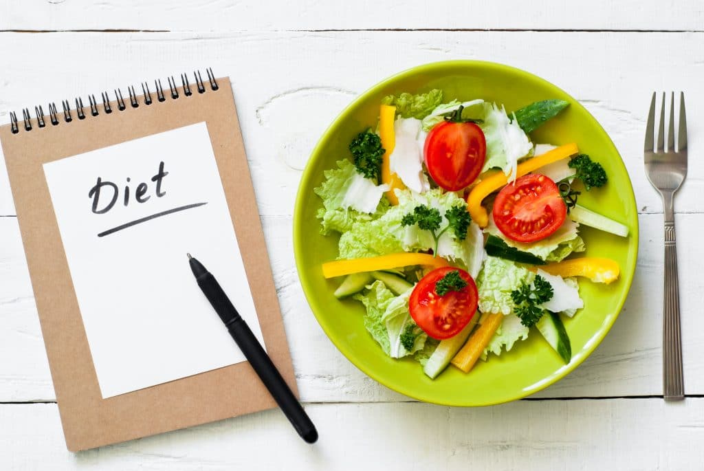 Healthy eating and Diet concept. Green Plate with fresh vegetables salad on wooden table.