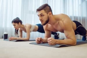 Morning fitness workout of family couple at home. Active man and woman in sportswear doing push up exercise in their house, healthy lifestyle, physical culture