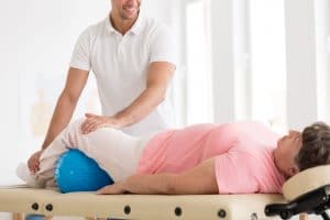 Can I Get Adjusted if I Have Osteoporosis?Smiling therapist massaging an old woman with osteoporosis using a blue ball