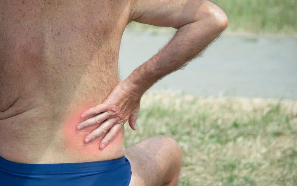 Elderly person holding hand for an inflamed place on the lower back