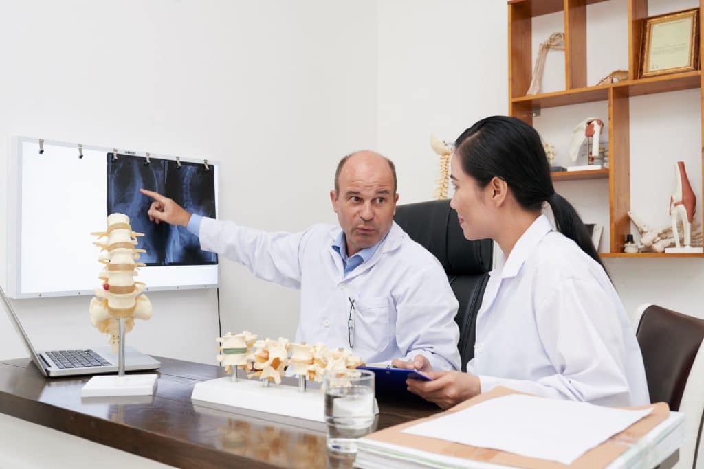 Chiropractors analyzing spine x-ray on the wall