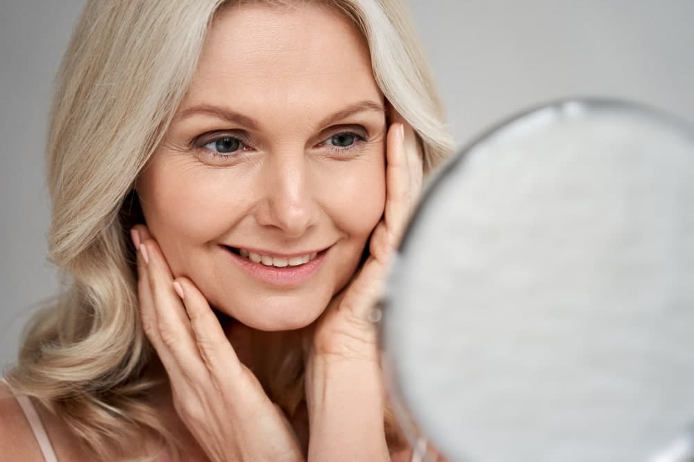 Smiling Woman Admiring Her Face Skin In The Mirrow